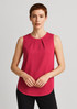 A sleeveless blouse in a rich pink colour featuring pleat detail at the front, modelled by a woman.