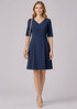 A navy short sleeve dress with a V-neck and a fitted waist, complemented by a neutral handbag.