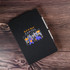 A black A5 notebook featuring a colourful logo with bull and bear illustrations on the cover.