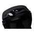 A black backpack with a zippered compartment, containing a pair of sunglasses. It features a logo on the exterior.
