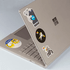 A silver laptop covered in various colourful stickers, including cartoon characters and logos.