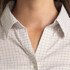 A close-up of a women's button-up shirt featuring a check pattern in light colours and a collar.
