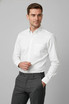 A white long sleeve button-up shirt with a pocket, paired with grey trousers. The shirt features a logo.