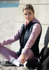 A navy vest worn over a pink top, featuring a model sitting on the sand, with athletic pants and a sporty look.