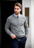 A grey knit sweater worn by a man, featuring a crew neck and long sleeves, paired with a collared shirt.