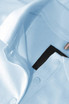 A light blue polo shirt featuring a collar, buttons, and an internal label, with a logo visible.
