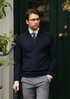 A stylish navy 1/4-zip men’s knitwear, paired with a shirt and grey trousers, featuring a logo on the chest.