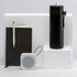 A black drink bottle, a black notebook, a white speaker, and a pen displayed on white pedestals.
