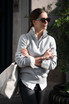 A grey unisex sweatshirt with a half-zip collar, worn by a person with sunglasses, carrying a large bag.