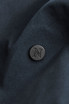 A close-up of a dark navy fabric with a round black logo badge embossed with the letter "N".