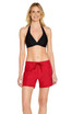 A woman models red cargo board shorts, paired with a black halter bikini top. The shorts feature a drawstring waist and a logo.