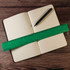 A green recycled plastic ruler measuring 30cm rests across an open dotted notebook and a black pen. A green recycled plastic ruler measuring 30cm rests across an open dotted notebook and a black pen.