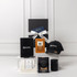 A gift pack featuring a black cap, notebook, candle, and assorted packaged items, all presented in a sleek box with a bow.