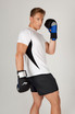 A man in a white and black T-shirt poses with boxing gloves, featuring blue accents, against a neutral background.