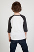 A back view of a kid wearing a white and dark grey 3/4 raglan sleeve t-shirt, paired with dark blue jeans.
