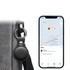 A black tracking tag attached to a bag, with a smartphone displaying a map and item location.