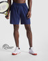 Navy sports shorts with an elastic waistband, held by a person holding a tennis racket. Features a logo.