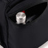 A black travel duffel featuring a zippered pocket with a silver drink bottle and a phone inside.