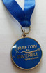 A blue soft enamel medal with an epoxy finish, featuring a silver loop and ribbon. It includes a logo and text.
