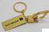 A gold keyring featuring a miniature excavator attached to a rectangular tag with a logo.