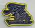 A soft enamel lapel pin featuring a motorcycle design in blue and yellow with a logo. No epoxy finish.