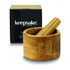 A wooden mortar and pestle set in a round bowl, displayed with a black box featuring a logo.