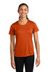 A woman wearing an orange Sport-Tek Ladies PosiCharge Competitor Tee, standing with a smile. The shirt has short sleeves.