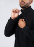 A man in a black polar fleece half zip top, adjusting the zip at the collar. The top features a logo.