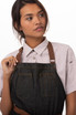 A dark denim apron with brown leather straps, featuring two front pockets.