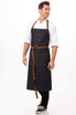 A denim chef's bib apron with brown straps, featuring pockets and a logo on the chest.