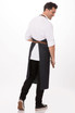 A dark denim bib apron with a brown belt, worn by a person turned slightly away from the camera.