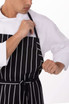 A black and white striped chef apron worn over a white shirt, featuring a tie and a logo.