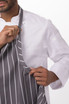 A grey and white striped chef apron being worn over a white shirt, featuring a logo or branding detail.
