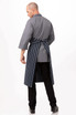 A grey chef apron with navy stripes, featuring half sleeves and a tied back, worn by a male model.