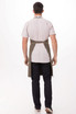 A person wearing a green Dorset Bib Apron over a light-coloured shirt and dark jeans, viewed from the back.