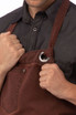 A burgundy Dorset Bib Apron with a silver ring detail, featuring a front pocket and adjustable straps.