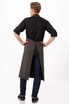 A dark grey chef's bib apron with a split back, worn by a person from behind, featuring a logo.