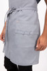 A light grey bib apron featuring a front pocket and a tie belt, part of the workwear collection.
