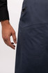 A dark blue bib apron with a side pocket, featuring a hand reaching toward it. The fabric appears durable.