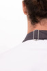 A close-up of the back of a white apron with a dark grey strap and a silver clip attachment.