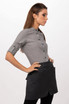 A woman wearing a grey top and a black half bistro apron, featuring pockets and buttons. The apron has a logo.