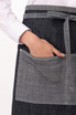 A dark denim half bistro apron with a contrasting lighter pocket and a tie at the waist. It features a logo on the pocket.