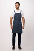 A navy blue Largo Bib Apron worn by a man, featuring adjustable straps and a sleek design.