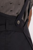 A close-up of a navy Largo Bib Apron featuring adjustable straps and a metal button detail.