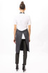 A grey Brio Bib Apron worn over a white shirt, featuring a back tie and styled with black pants and boots.