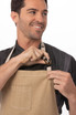 A man wearing a beige apron with a pocket and a logo, adjusting the neck strap.