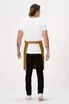 A man standing with his back to the camera, wearing a mustard-coloured Lockharte bib apron over a white shirt and black jeans.