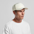 A white perforated cap featuring a structured front. The cap has a logo and is paired with a plain white T-shirt.