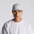A white nylon cap with a logo, worn by a model in a plain white t-shirt.