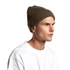 A ribbed olive green beanie is worn by a model, featuring a snug fit. The product has a logo.